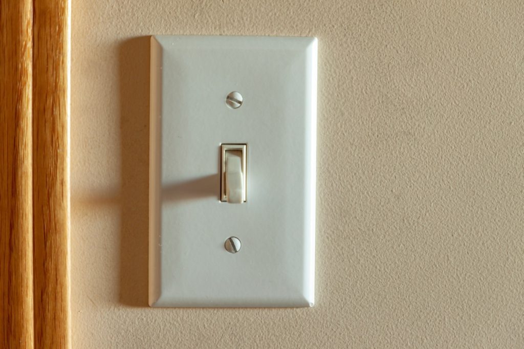 An old North American light switch on a wall near a doorway, highlighting when to call Dustmen Electric for residential troubleshooting and repair.