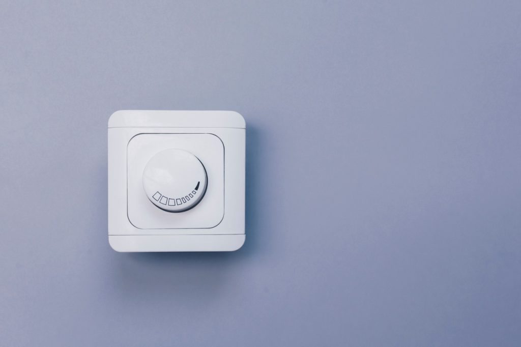 A round rolling dimmer switch installed on a clean wall, highlighting professional inspection and electrical troubleshooting by Dustmen Electric.