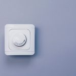 A round rolling dimmer switch installed on a clean wall, highlighting professional inspection and electrical troubleshooting by Dustmen Electric.