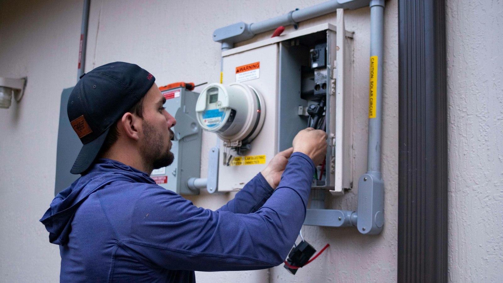 Electrician checking residential electrical equipment near a home